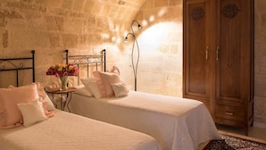 Un dormitorio con dos camas, un armario de madera y una pared de piedra.