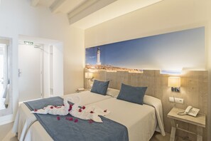 A hotel room with two beds, a painting of a lighthouse, a phone on the nightstand, and a sign indicating the exit.