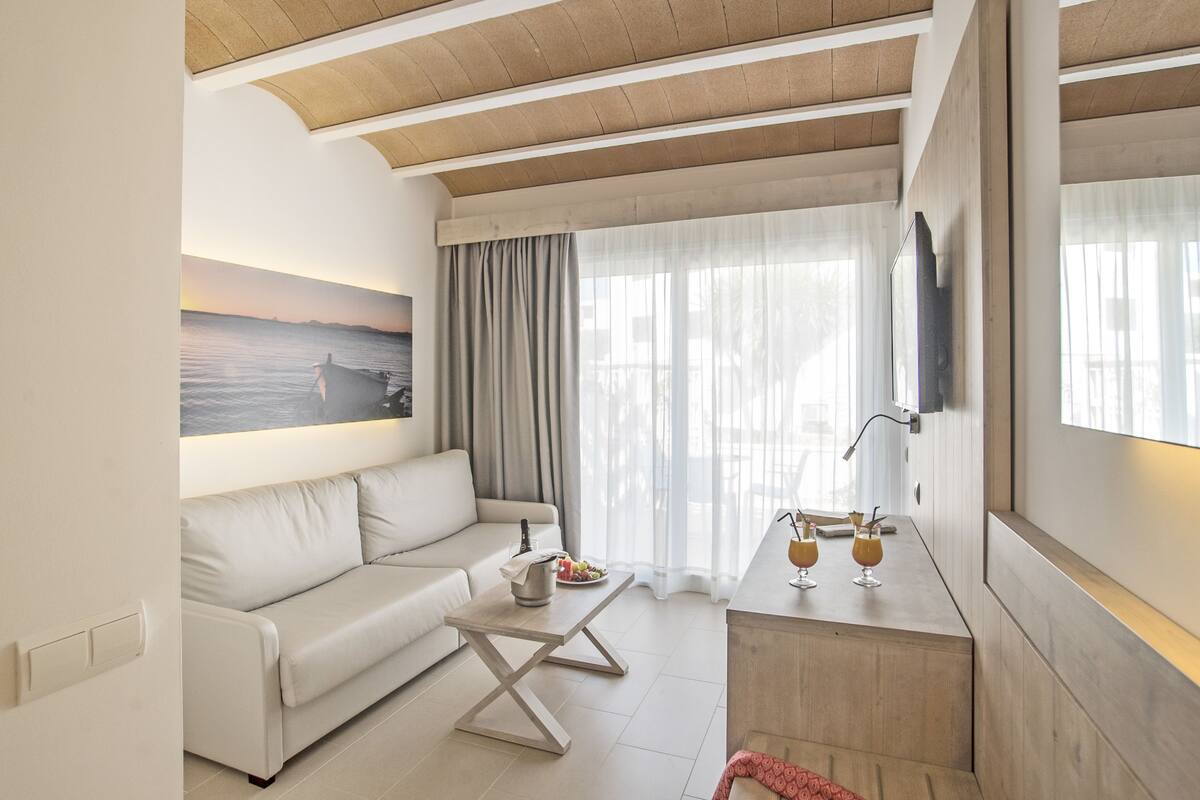 Ein modernes Wohnzimmer mit einer Couch, einem Couchtisch und einem an der Wand montierten Fernseher.