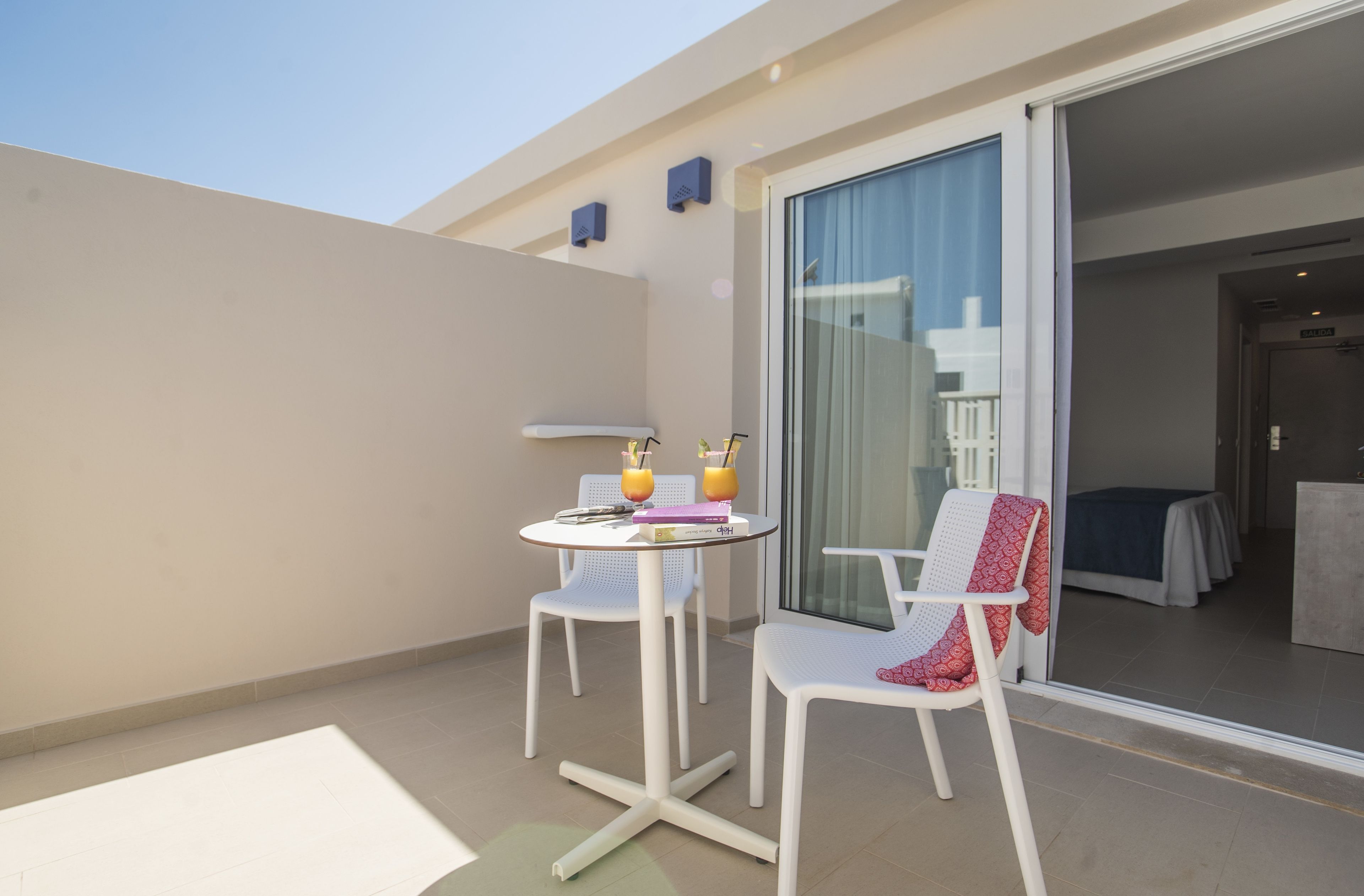 A balcony with a table and chairs, a sliding glass door, and a view of the interior.