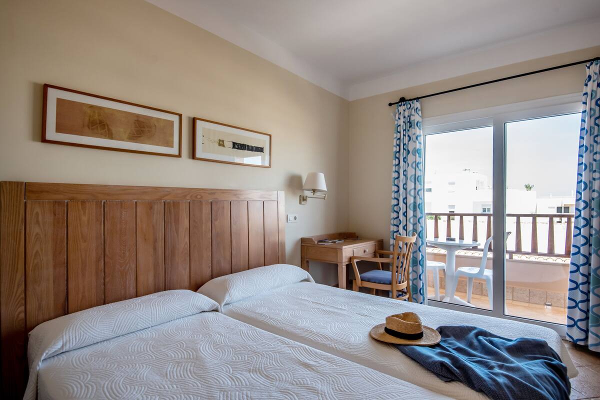 Ein Hotelzimmer mit einem großen Bett, einem Schreibtisch und einem Balkon mit Stühlen.