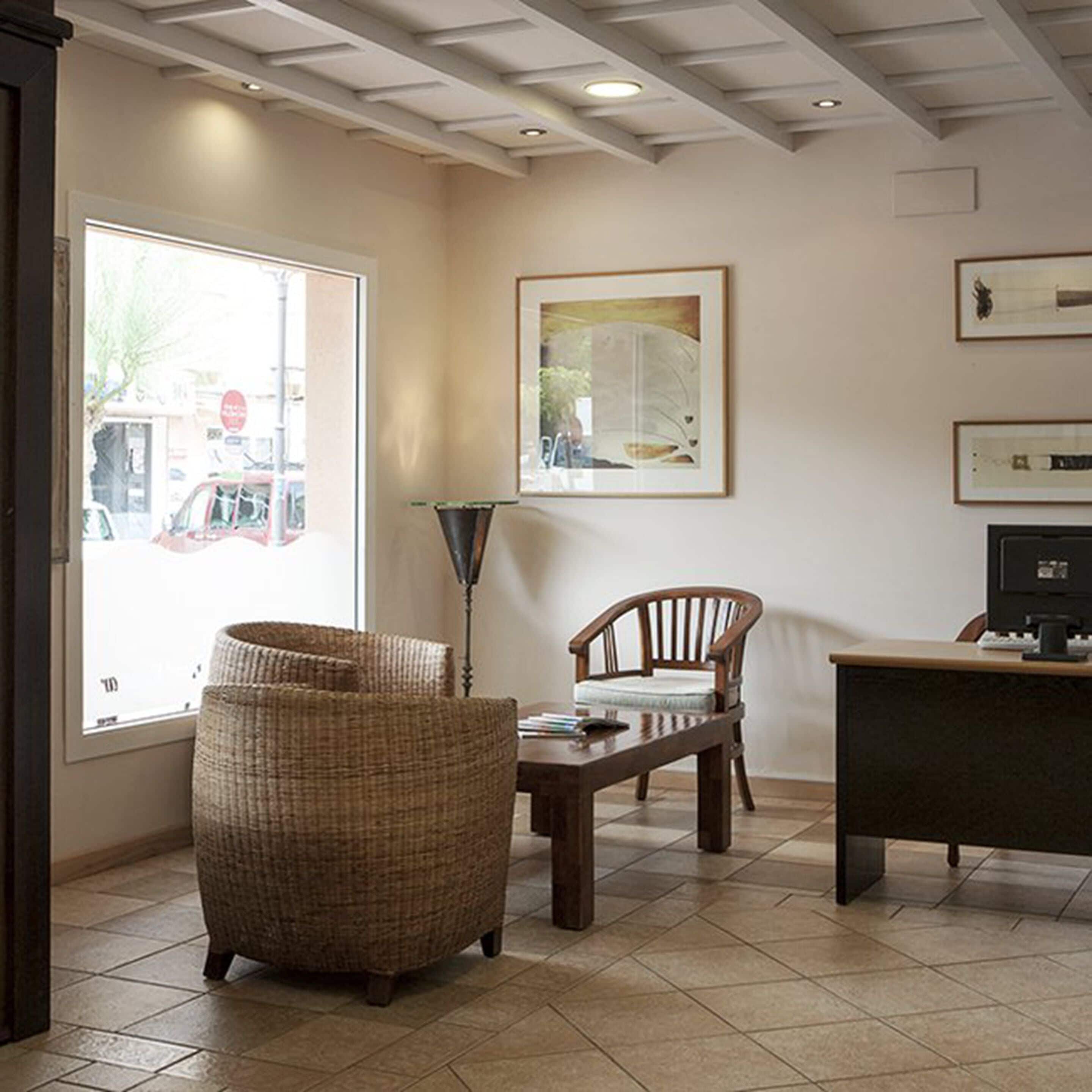A room with a wicker chair, a desk, and a framed artwork on the wall.