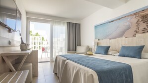 Una habitació d'hotel amb un llit, un escriptori i un balcó amb vista a la platja.