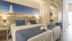 Habitació d'hotel amb un llit gran, una tauleta de nit, una làmpada penjada a la paret i una vista d'un far per la finestra.