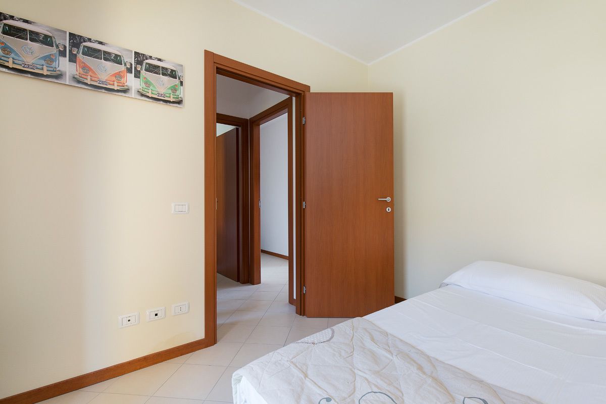 Une chambre à coucher avec un lit, une armoire en bois et une porte donnant sur une autre pièce.