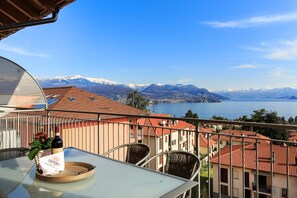A balcony with a table, chairs, and a bottle of wine. - Impero House Rent - Belvedere (Stresa)