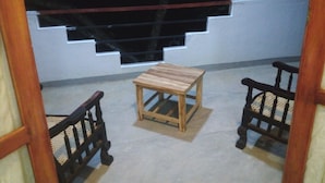 Un pequeño espacio exterior con mesa de madera y dos sillas, una escalera y barandilla.