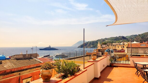 A terrace with a view of the sea, a yacht, and a cityscape in the background. - Enzo Il Negro (Lipari)