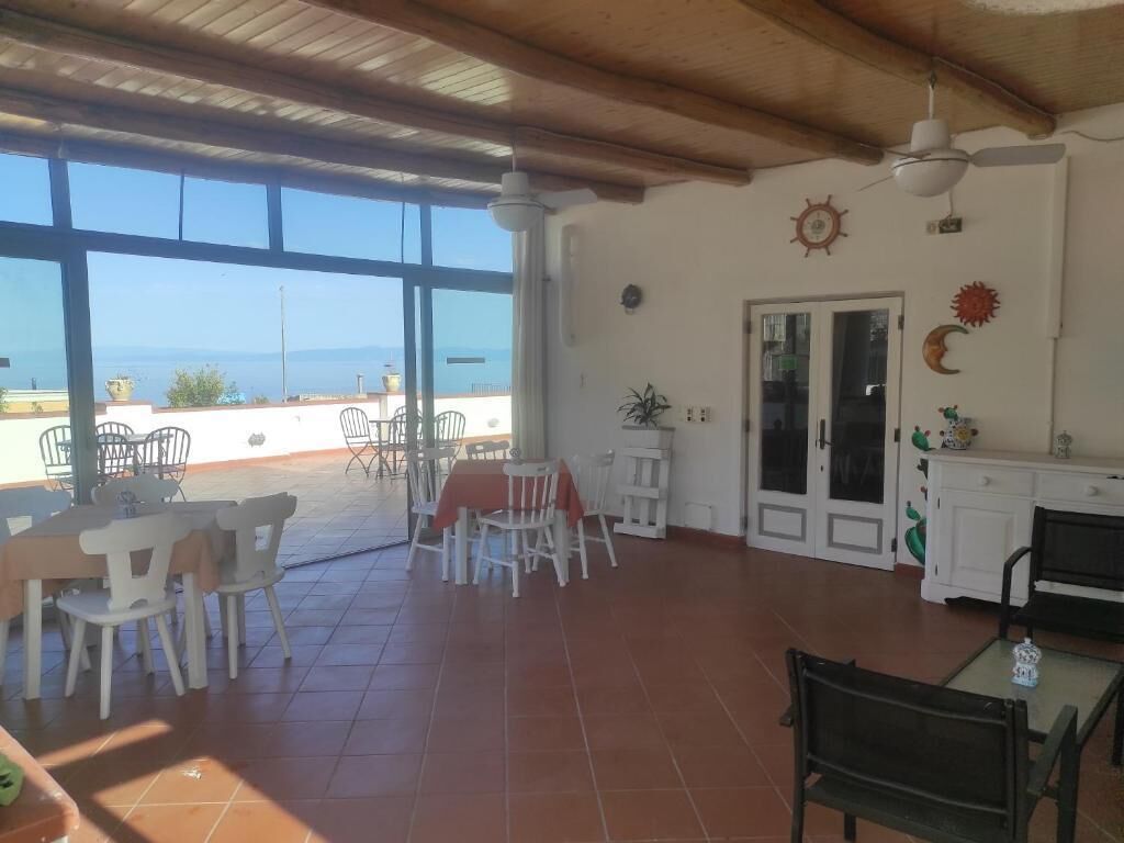 A spacious patio with a dining area, a kitchen, and a view of the sea.