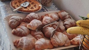 A buffet table with various food items including pastries, fruits, and a container of granola. - Enzo Il Negro (Lipari)