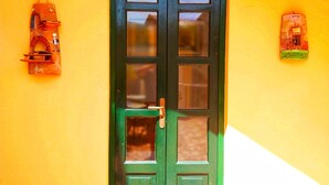 A green door with a handle, set in a room with a yellow wall and a white baseboard. - Enzo Il Negro (Lipari)