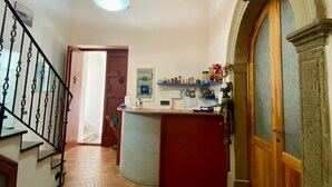 A hallway with a wooden staircase, a reception desk, and a patterned rug. - Enzo Il Negro (Lipari)