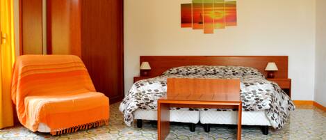 Un dormitorio con una cama, una mesita de noche de madera, una silla, un armario y una pared decorada con un cuadro de atardecer.