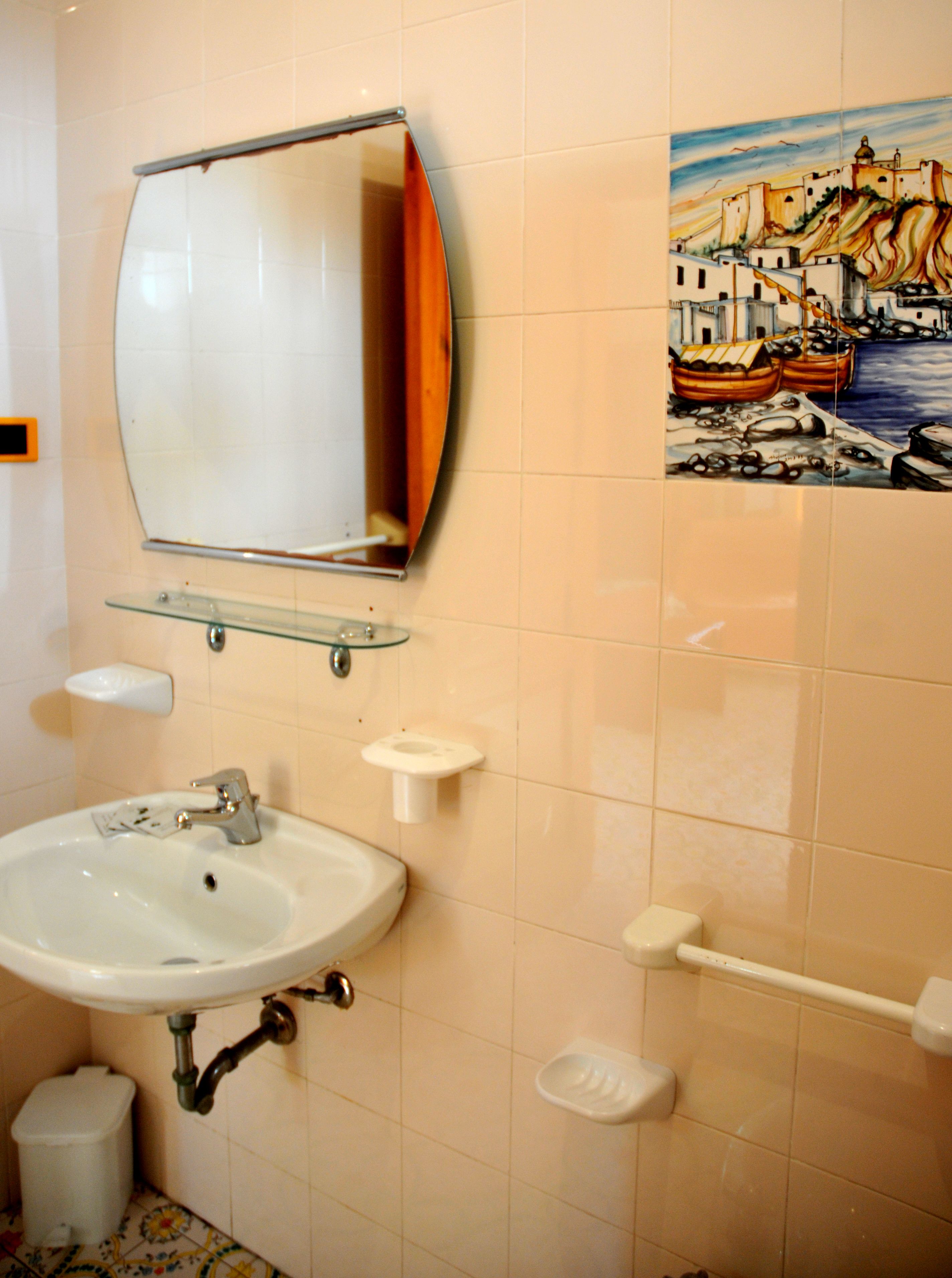 A bathroom with a white sink, mirror, and tiled walls.