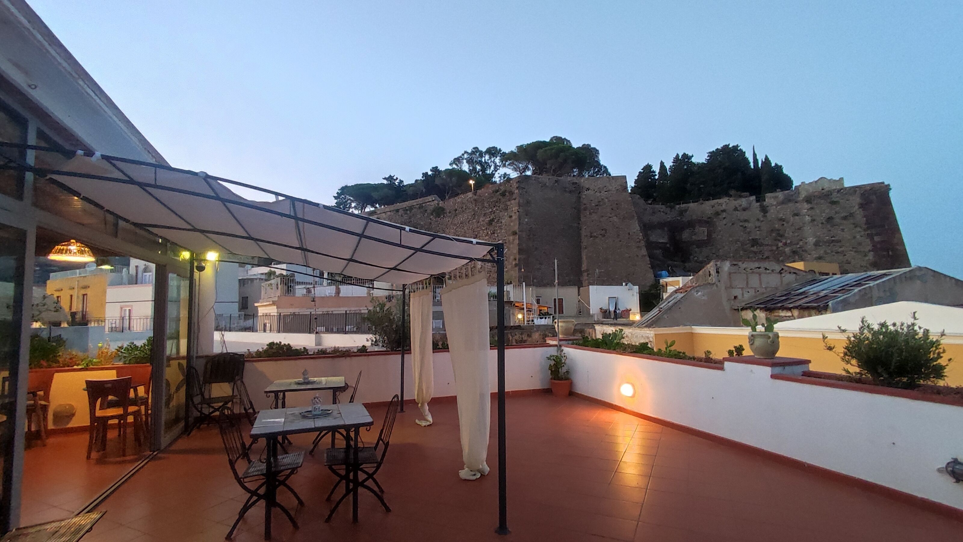 An outdoor patio with a table and chairs, a pergola, and a view of a historic building.
