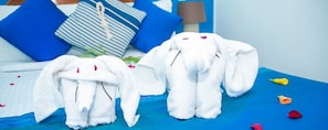 A bed with blue bedding and two white towels shaped like elephants. - Ayati Hotels (Flic-en-Flac)