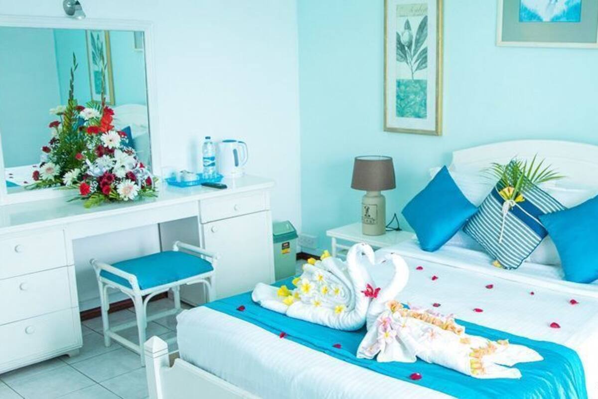 A bedroom with a bed, a desk, a chair, a nightstand, and a lamp.