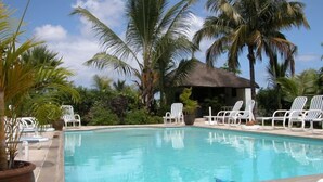 A swimming pool with white lounge chairs and palm trees. - Ayati Hotels (Flic-en-Flac)