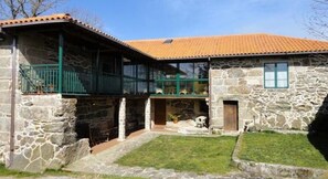A stone house with a tiled roof, a balcony, and a small front yard. - Rectoral de Candas (Rairiz de Veiga)