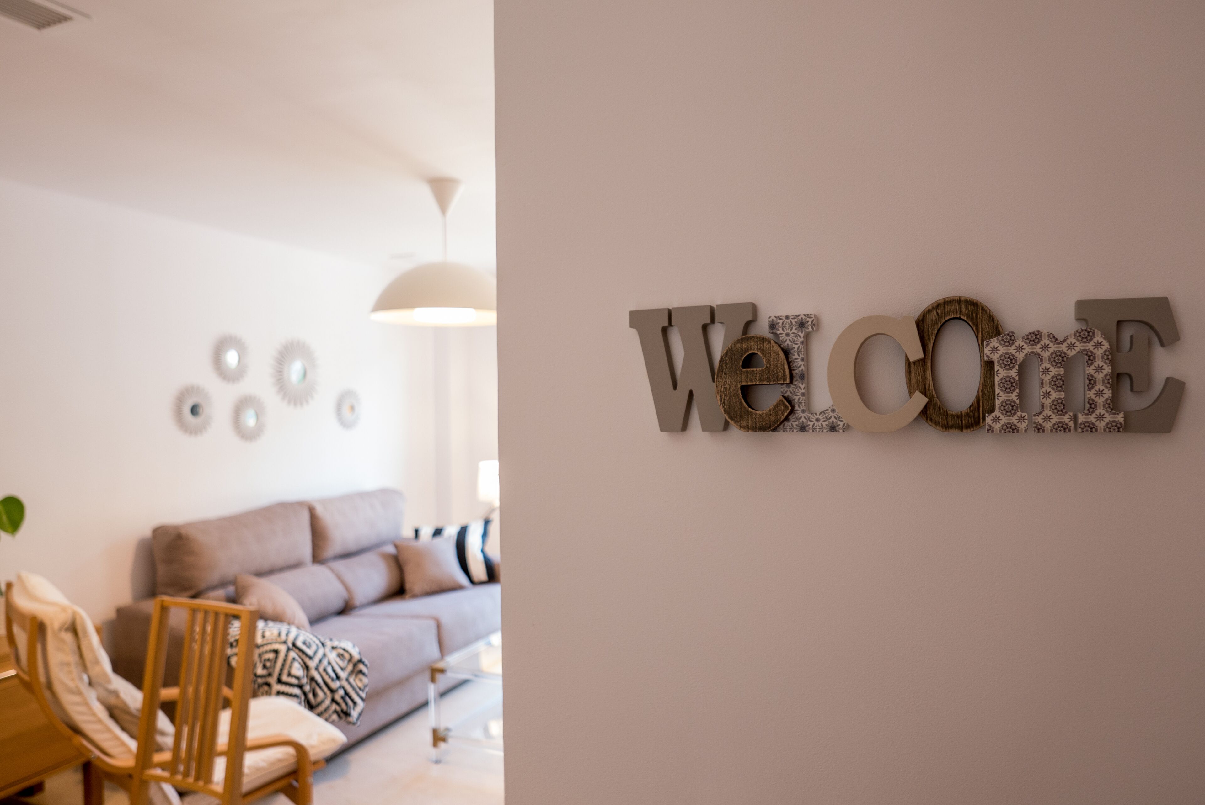 A modern living room with a sofa, a wooden chair, and decorative wall art.