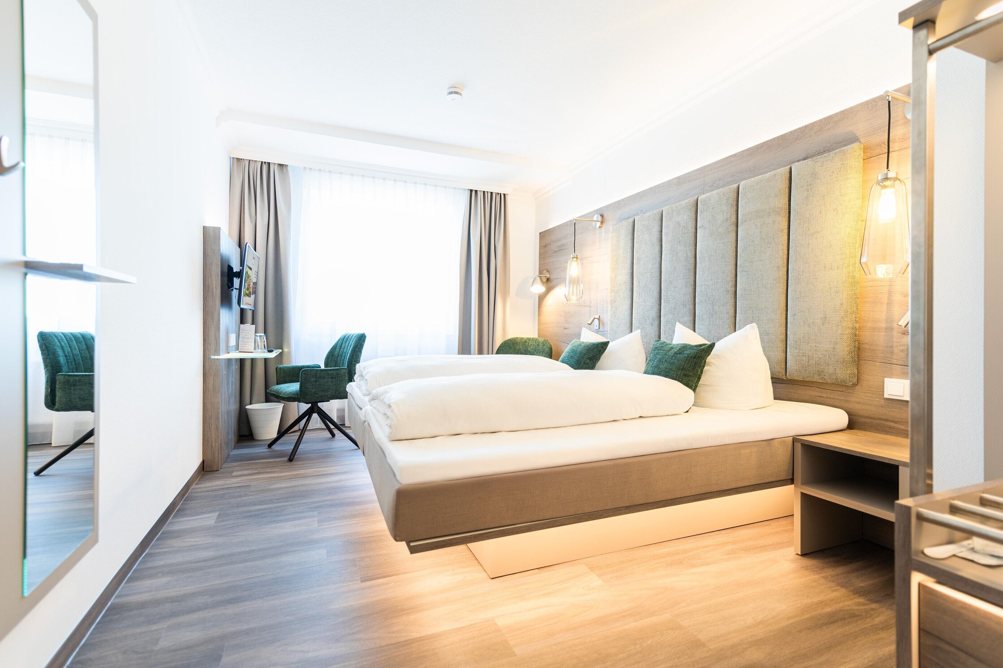 A modern hotel room with a large bed, a desk, and a seating area.