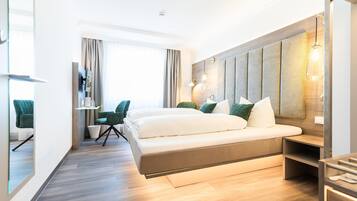 A modern hotel room with a large bed, a desk, and a seating area.