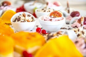 A variety of desserts in bowls, including one with a halved fruit, surrounded by other fruits and berries. - Hotel Hennies (Isernhagen)