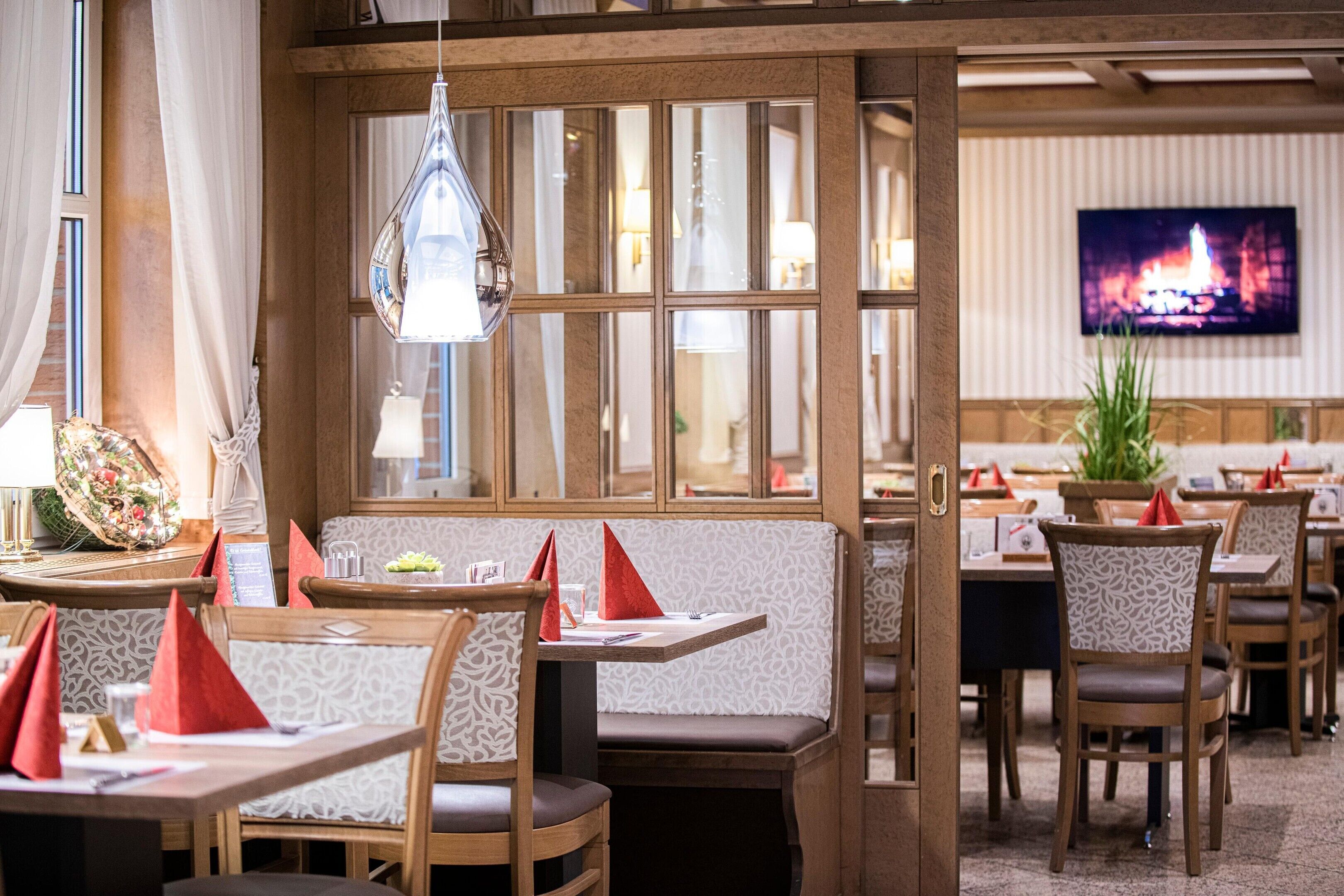 A restaurant interior with wooden booths, tables, and a television displaying a fire scene.
