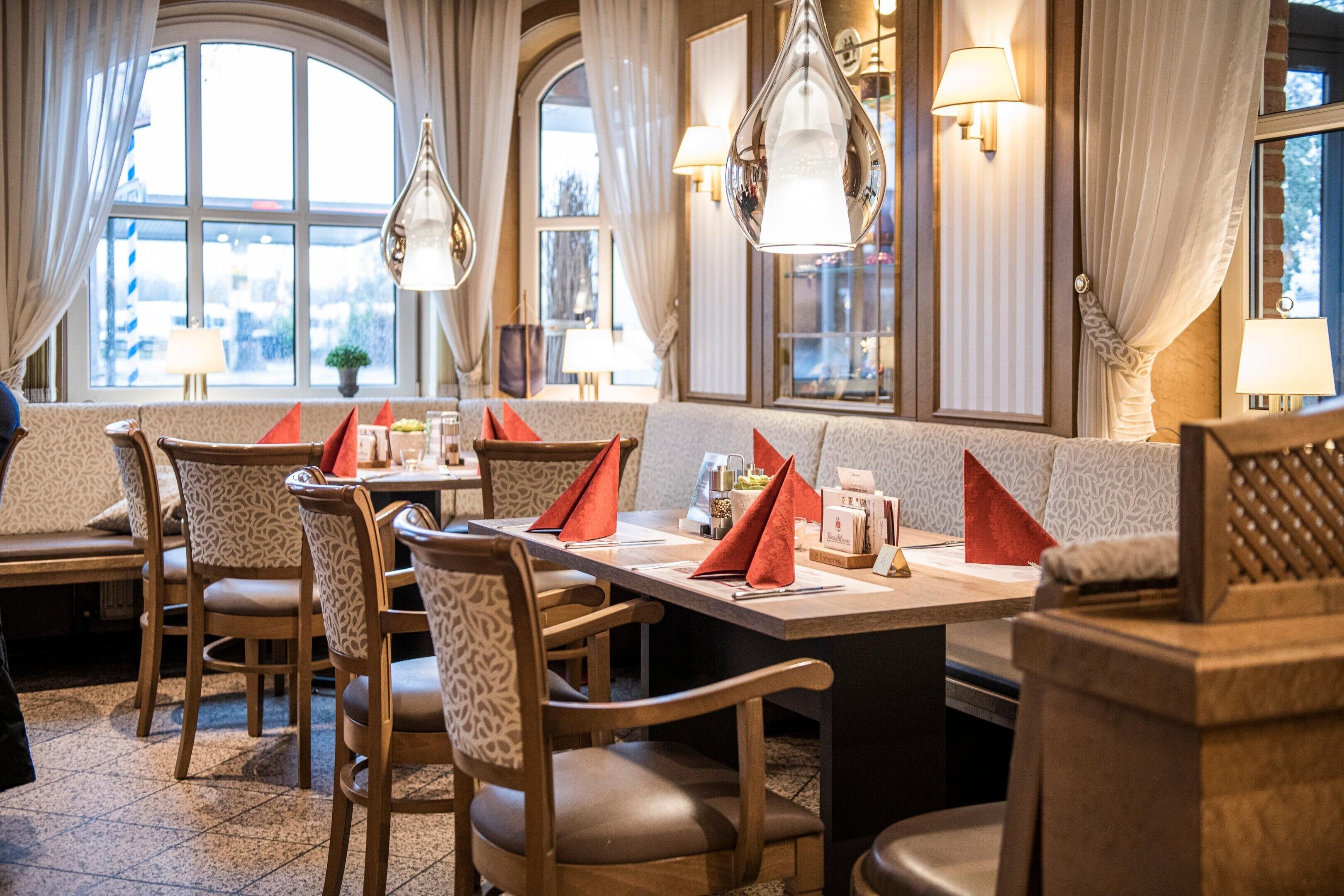 A restaurant interior with a long dining table, multiple chairs, and a bench seating area.