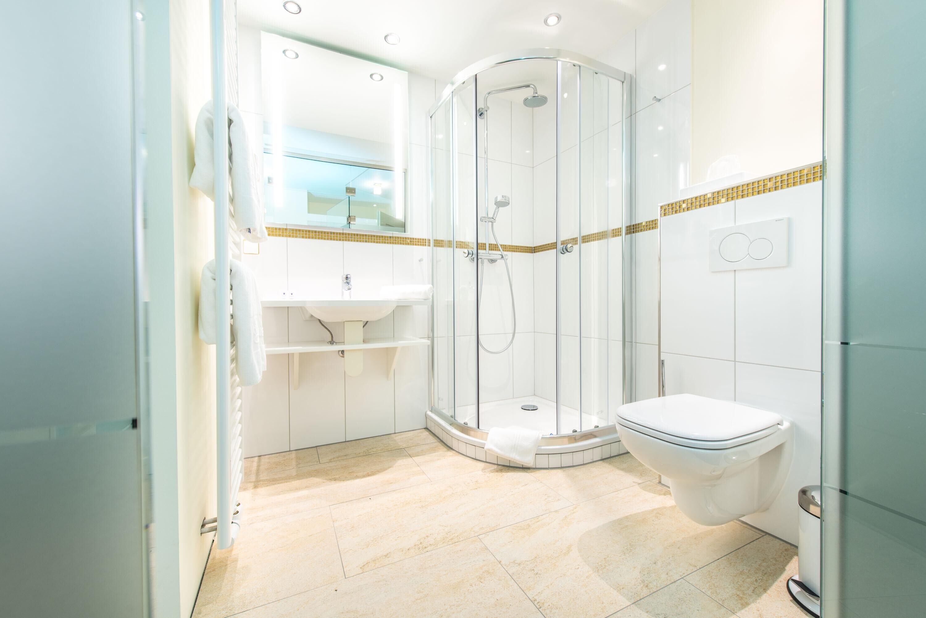 A modern bathroom with a glass-enclosed shower, a white sink, and a toilet.