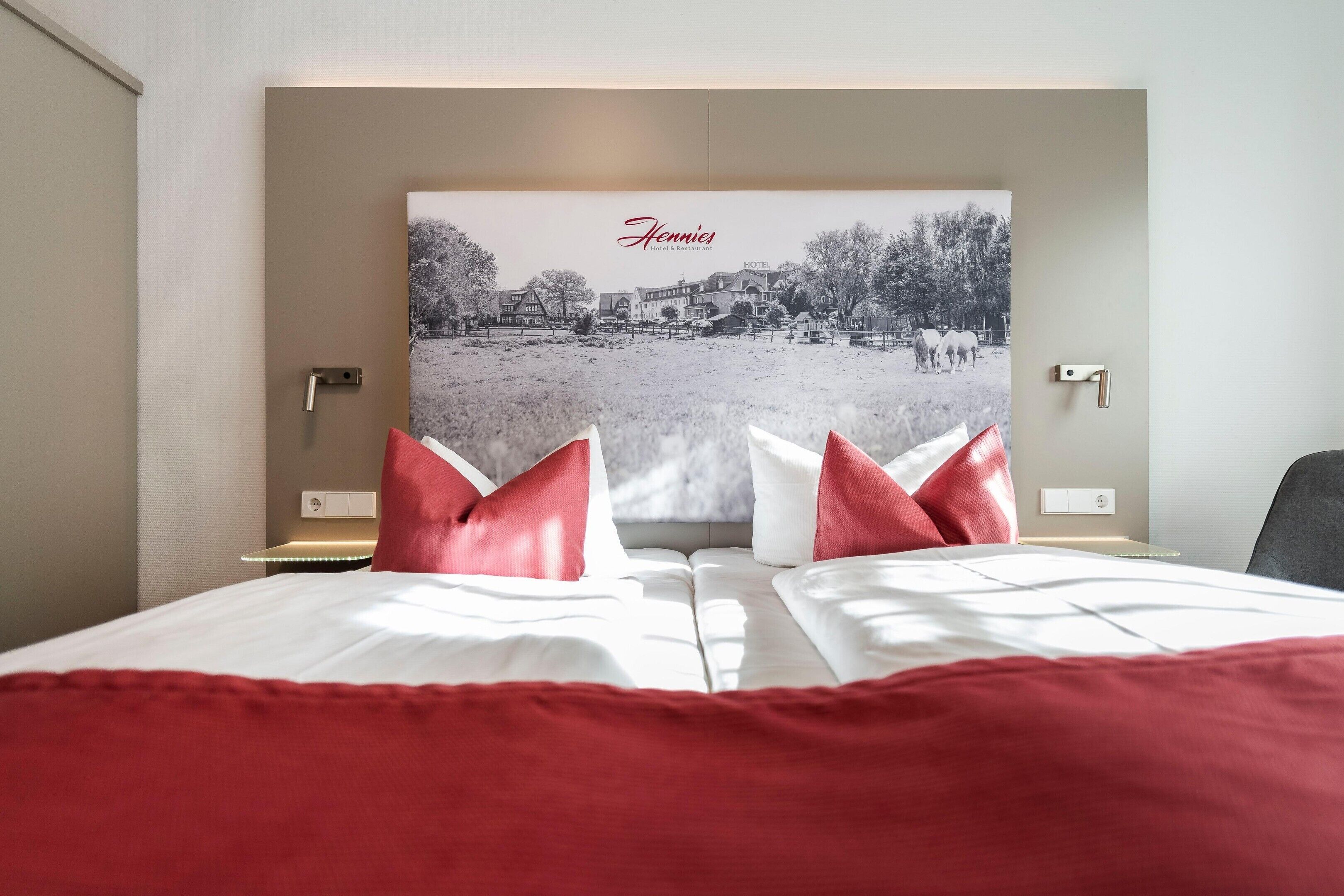 Una habitación de hotel con una cama, dos almohadas, una mesita de noche y un cuadro colgado en la pared.