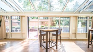 A spacious room with a large table and chairs, a skylight, and large windows offering views of the outdoors. - Hotel Hennies (Isernhagen)