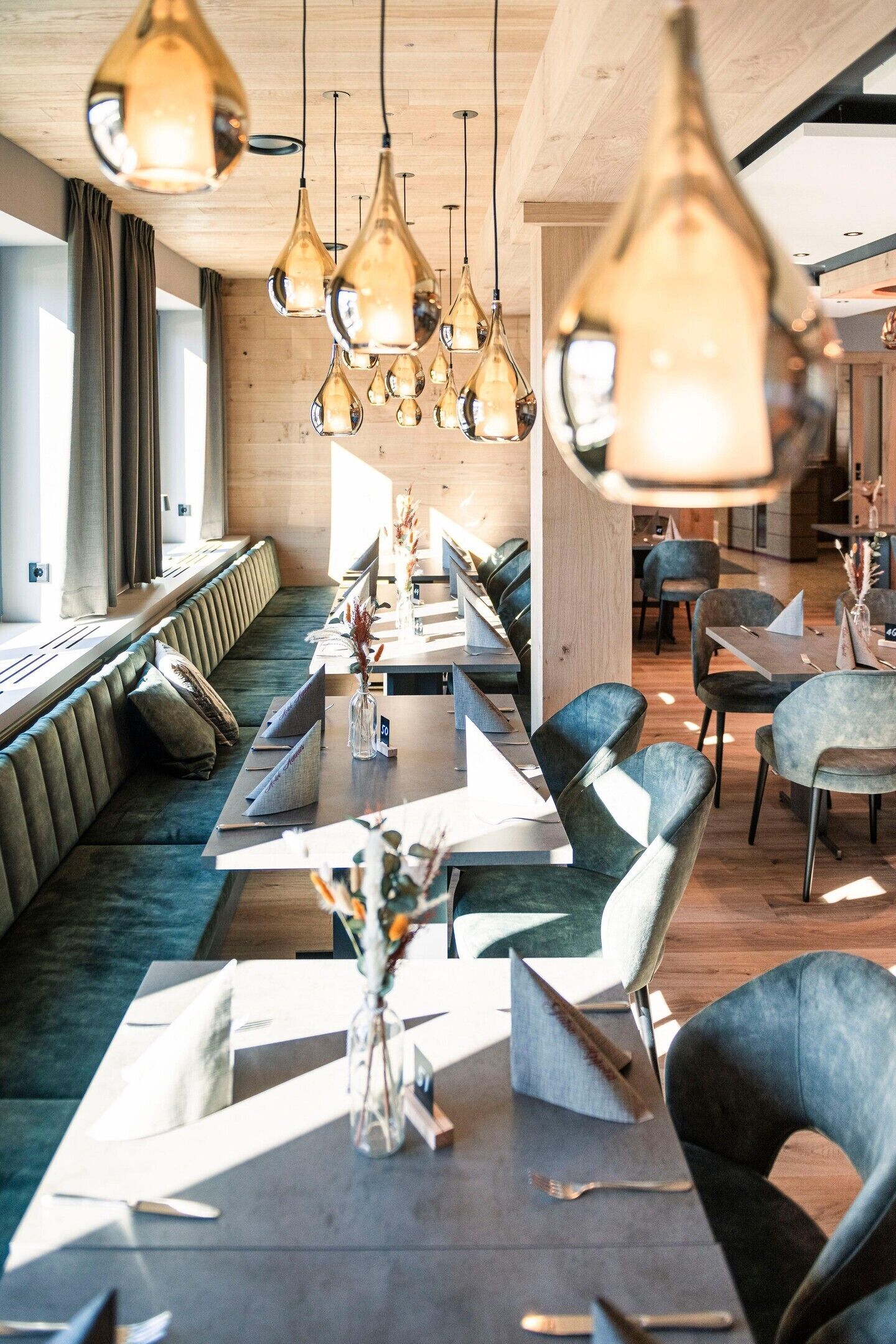 Un restaurante moderno con una mesa común alargada, asientos individuales e iluminación colgante.