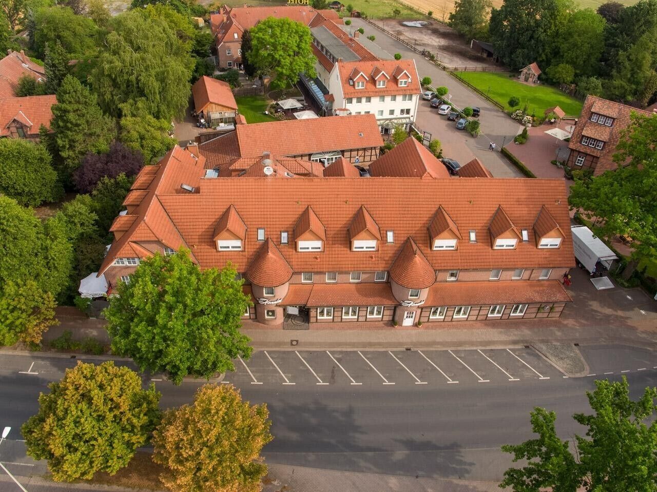 A hotel with a red-tiled roof, multiple stories, and a parking lot.