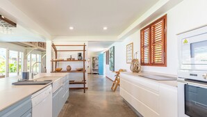 Una cocina moderna con armarios azul claro, una estantería de escalera de madera, una cafetera y un horno grande.