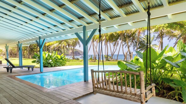 Una terraza de madera con piscina, un columpio y un banco.
