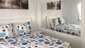 A bedroom with a bed, two pillows, a nightstand, and a large mirror. - Home from home 2 bed luxury apartment, heated pool. 202 (Puerto Del Carmen)