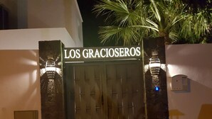 A gated entrance with a sign reading "LOS GRACIOSEROS" at night. - Home from home 2 bed luxury apartment, heated pool. 202 (Puerto Del Carmen)