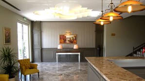 A reception area with a marble floor, a reception desk, a yellow armchair, and a painting on the wall. - Sarban Hotel (Fethiye)