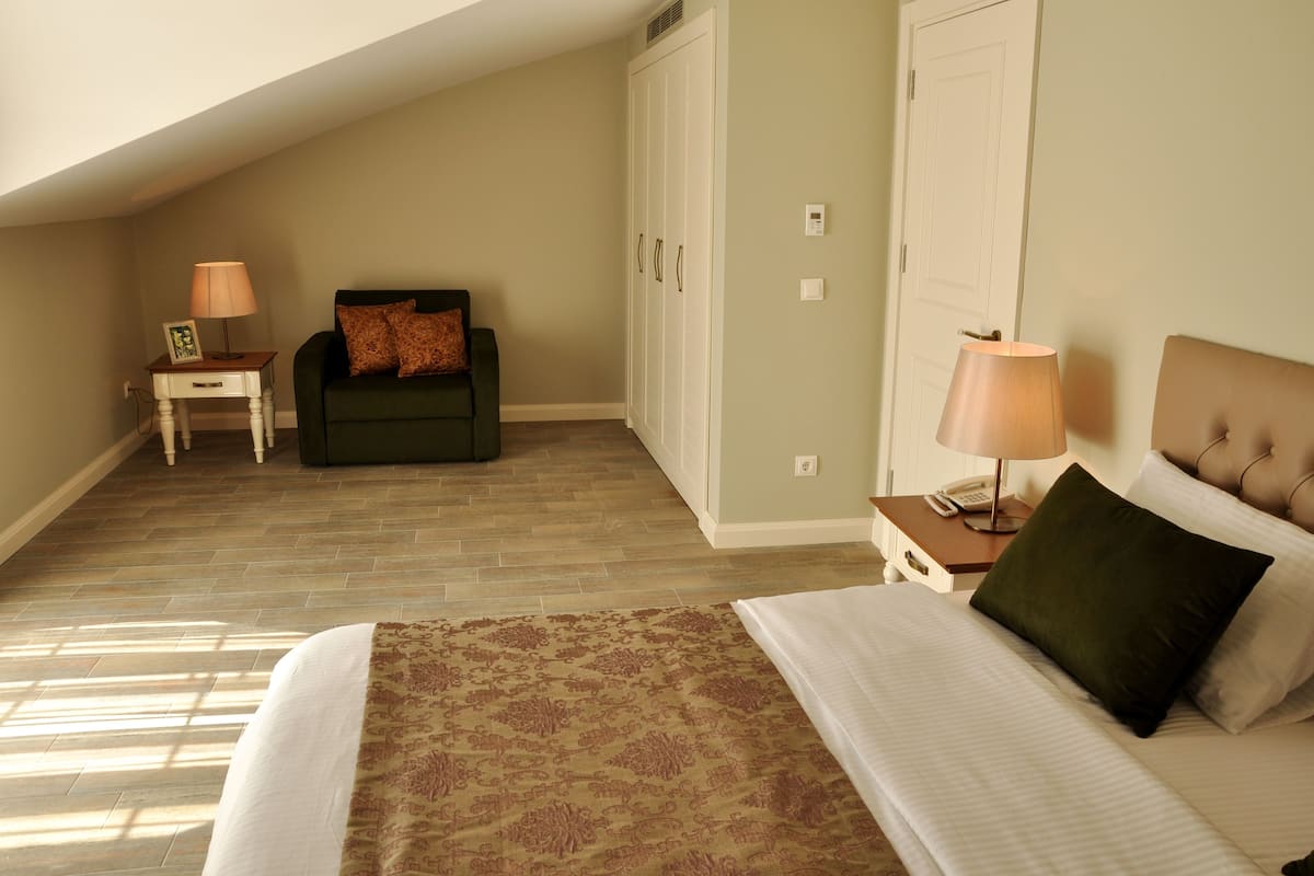 A bedroom with a bed, a nightstand, a dresser, a chair, and a wardrobe.