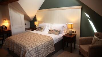 A bedroom with a large bed, two bedside tables with lamps, a chair, and a door.