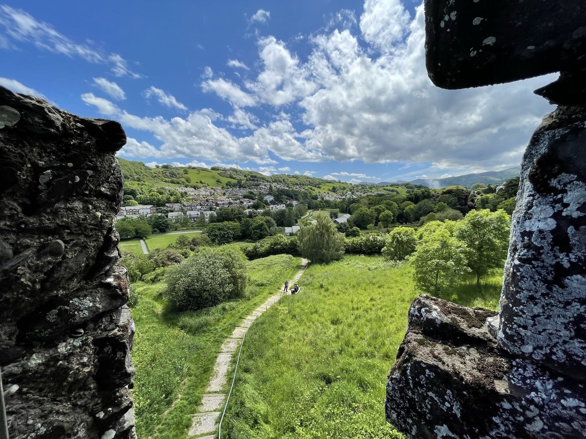 A stone structure with a pathway leading through a green landscape.