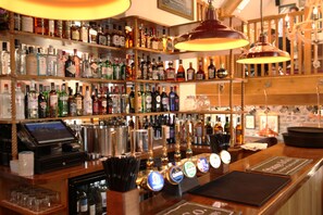 A bar with shelves of liquor bottles, a cash register, and a bar counter with a menu. - The Erskine Arms (Conwy)