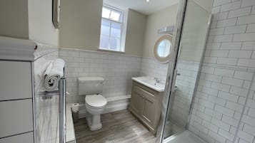 Un baño con inodoro, lavamanos y zona de ducha.