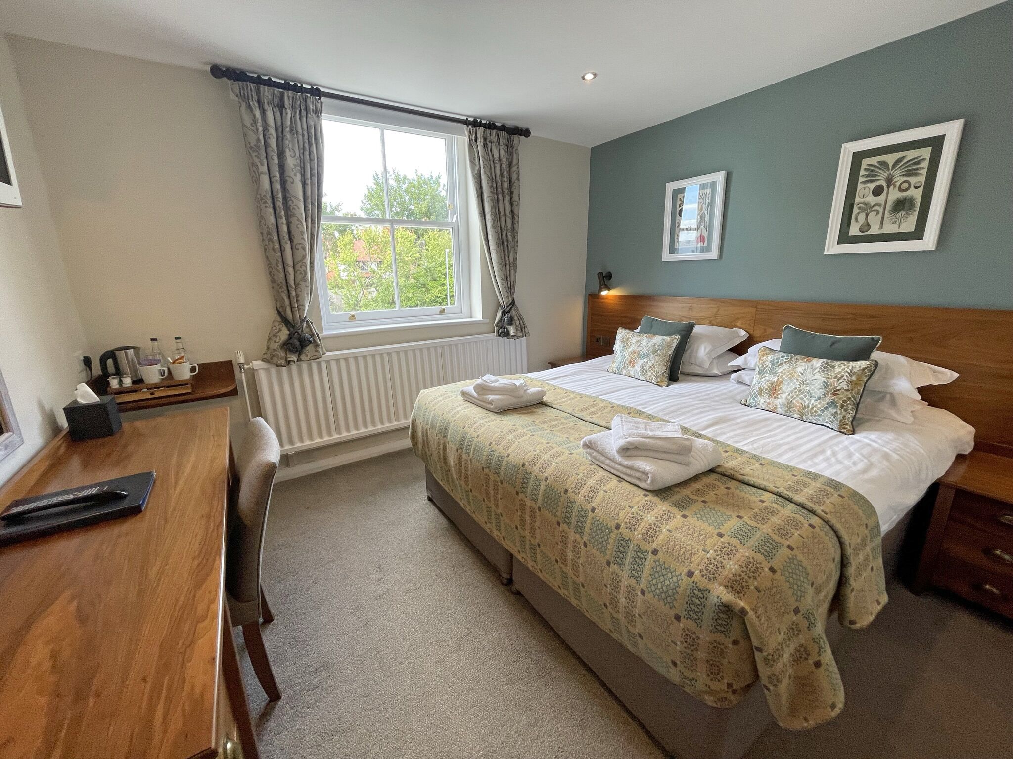 A neatly arranged hotel room with a bed, bedside table, and a window with curtains.