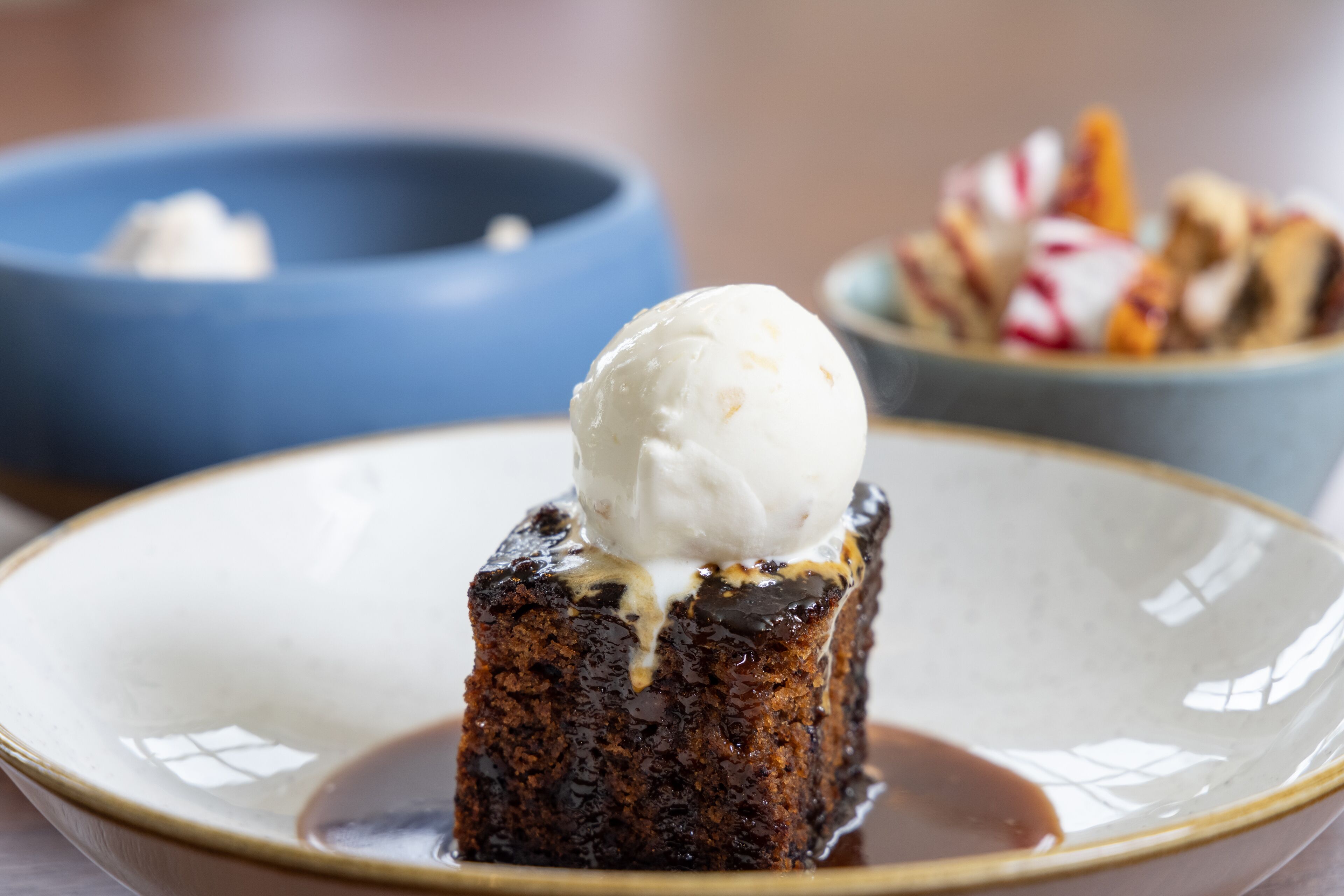 Een dessert met een bolletje ijs erop, geserveerd op een bord met saus.