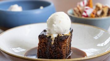 Un dessert con una pallina di gelato sopra, servito su un piatto con un filo di salsa.