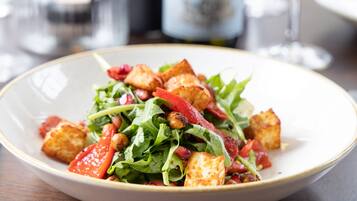 A plate of salad with croutons and tomatoes.
