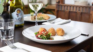 Een eettafel met een bord eten, een glas water, een fles wijn en een wijnglas.