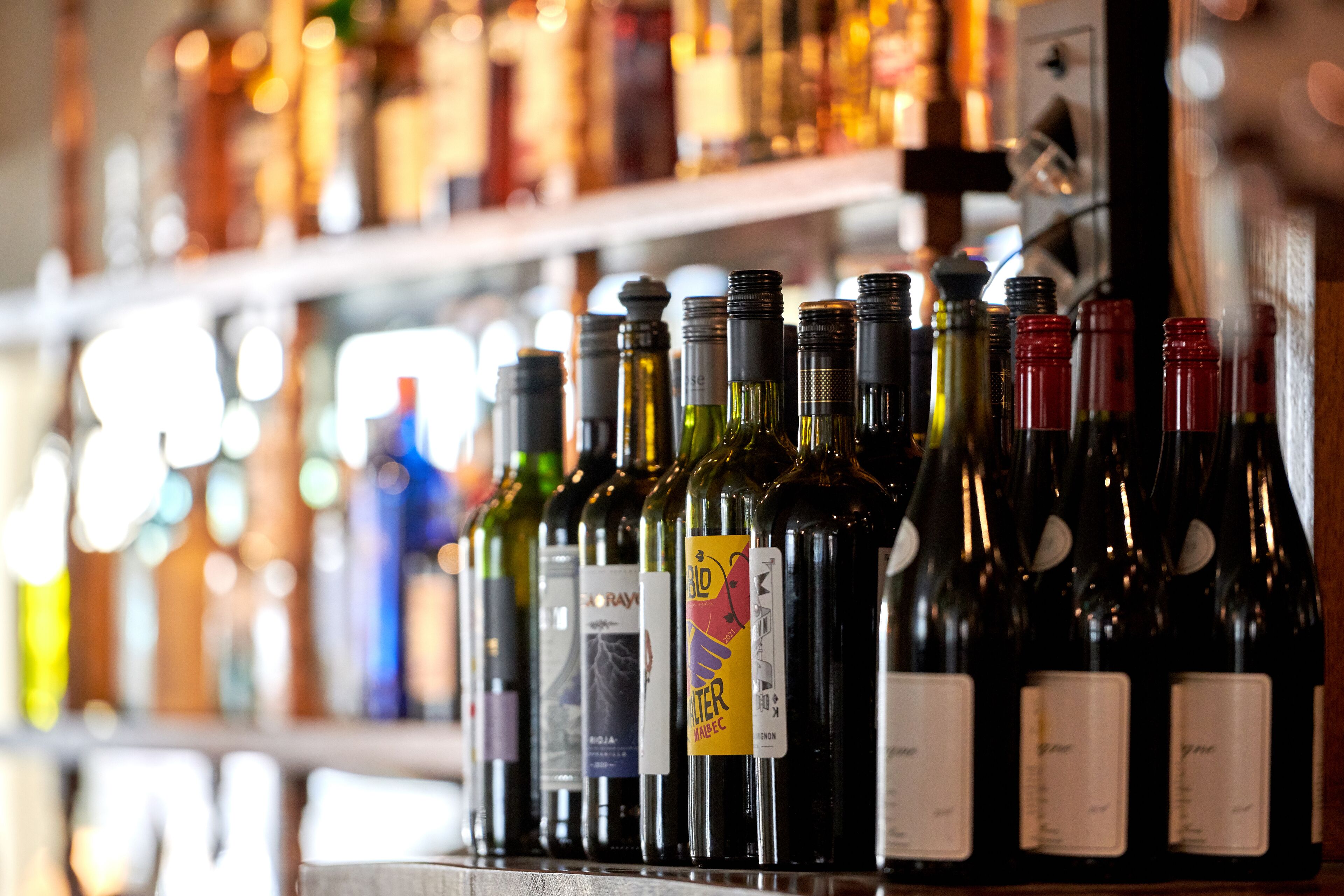 Várias garrafas de vinho numa prateleira, com etiquetas e etiqueta de preço.